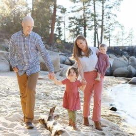 family of four walking together holding hands along the sandy beaches at lake tahoe