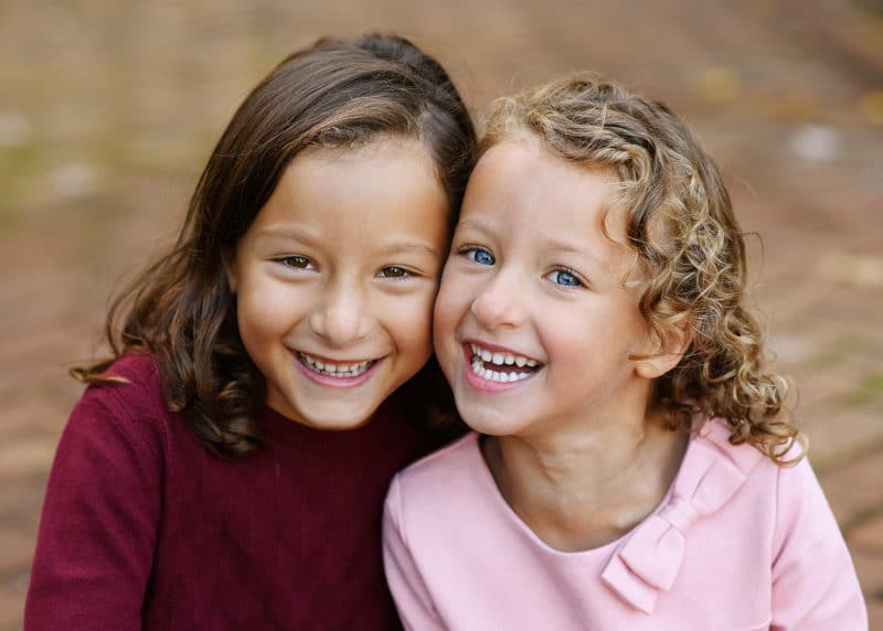 two young girls smiling together during fall family photos in empire mine california