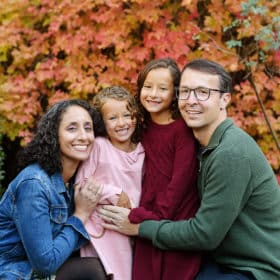 mom and dad with two young girls hugging for fall family photos in empire mine california