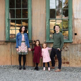 family of four posing together in front of big green windows in empire mine california