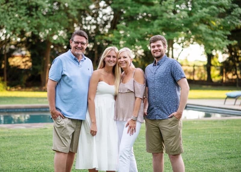 family of four standing in a grassy field by the pool in clarksburg california