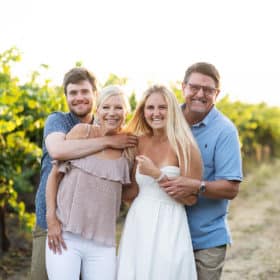 family of four laughing together in a vineyard in the summer sunset california