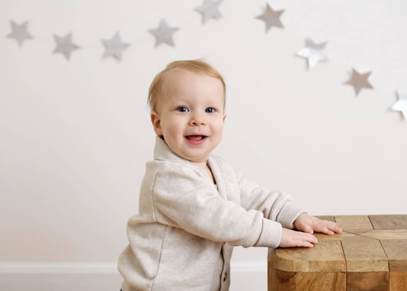 one year old boy standing with star garland behind him