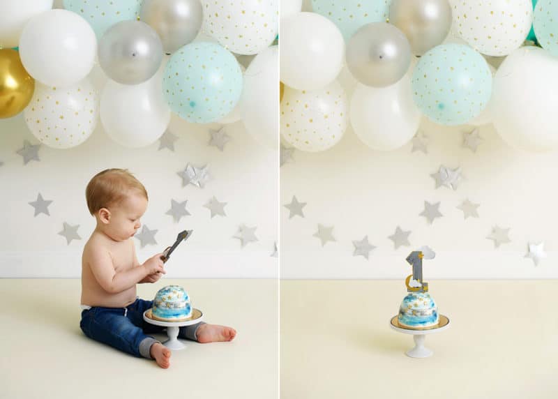 one year birthday cake in front of balloon garland, boy holding one year cake topper