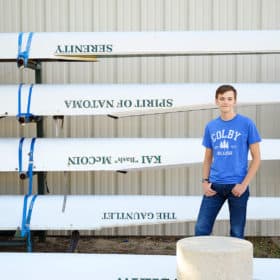 high school senior posing next to rowing boats in folsom california