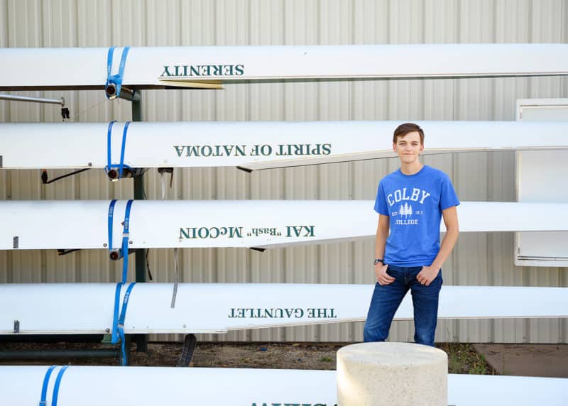 high school senior posing next to rowing boats in folsom california