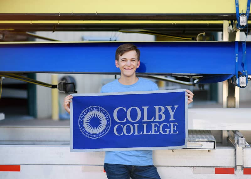 high school senior boy holding colby college flag during senior photo shoot in folsom california