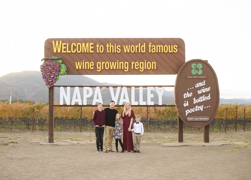 family of five standing in front of sign that says "welcome to this world famous wine growing region, Napa Valley"