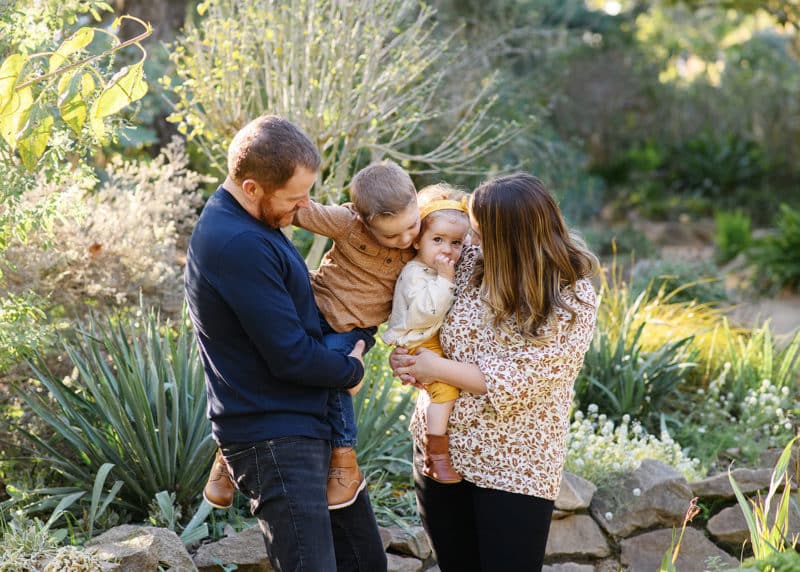 family of four hugging together and laughing in succulent garden in sacramento california