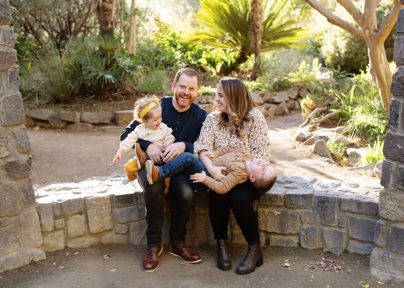 family of four sitting on a stone wall laughing together in sacramento california