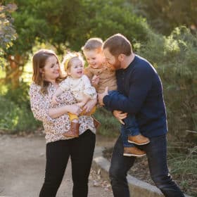 young family of four looking at each other and laughing during golden hour in sacramento california