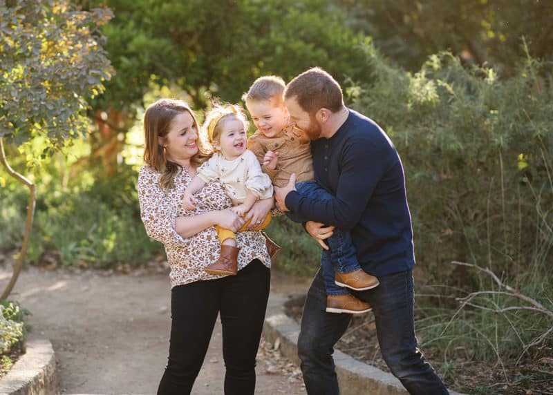 young family of four looking at each other and laughing during golden hour in sacramento california