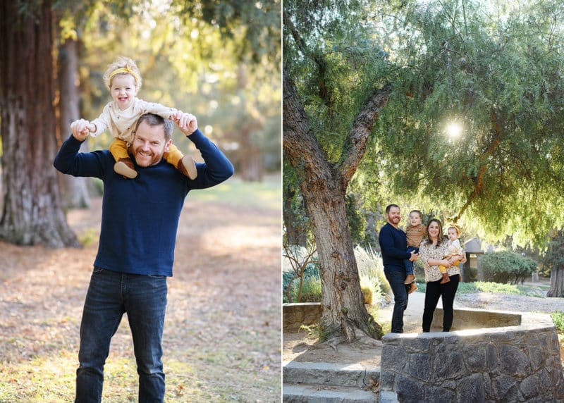 dad holding young daughter on his shoulders, family of four posing by a tree during fall family photos
