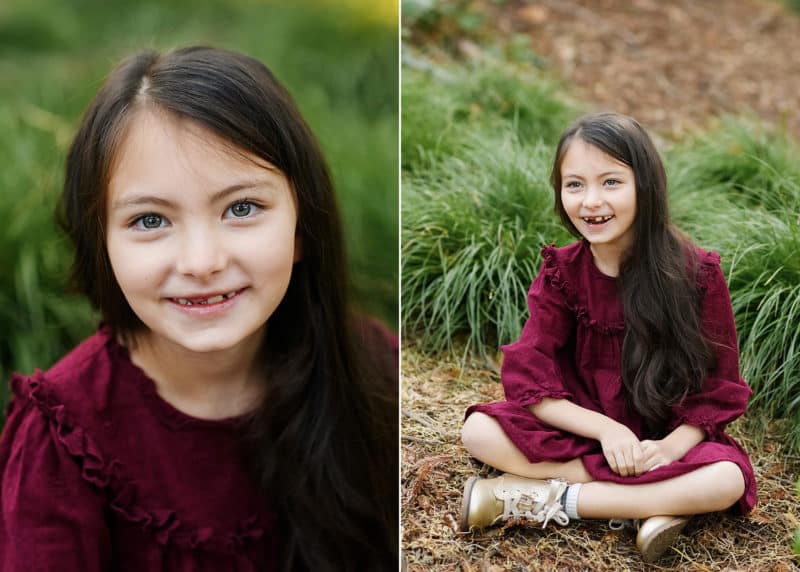 young girl sitting on the forest floor smiling during fall family photos in davis california