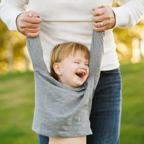 young boy being held up by mom laughing and smiling during fall family photos