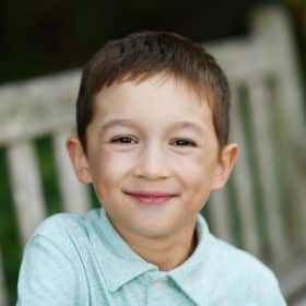 young boy sitting on a bench in berkeley califronia smiling during family photos