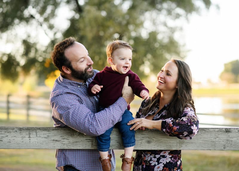 mom and dad looking at young son and laughing during outdoor fall photos