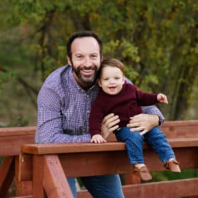 Dad holding young son on a wooden bridge during fall family photos in elverta california