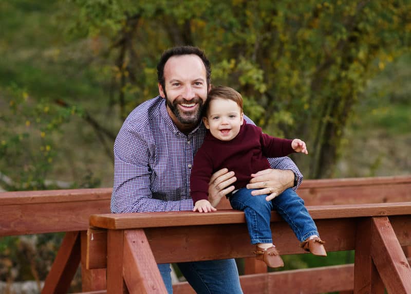 Dad holding young son on a wooden bridge during fall family photos in elverta california