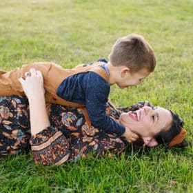 mom and young son laying in the grass and laughing together during fall family photos in sacramento california