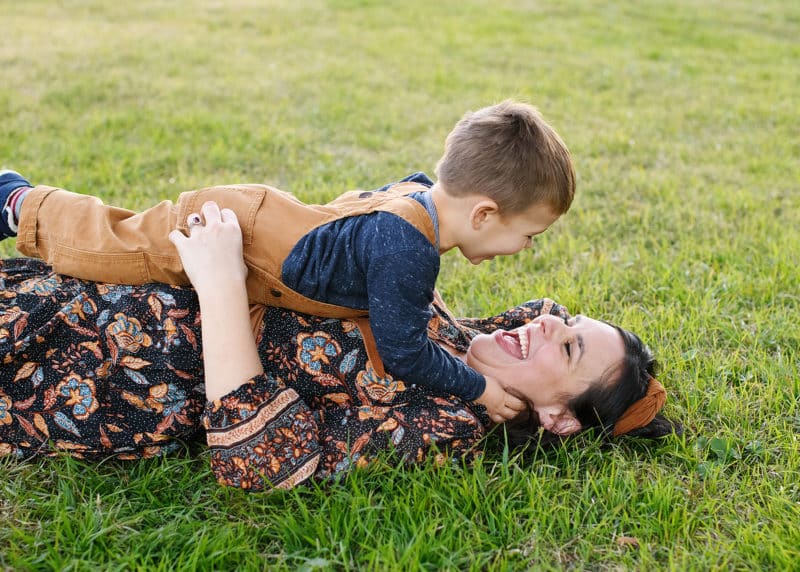 mom and young son laying in the grass and laughing together during fall family photos in sacramento california