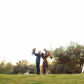 mom holding son, dad holding daughter in the air in a field in golden hour sacramento california
