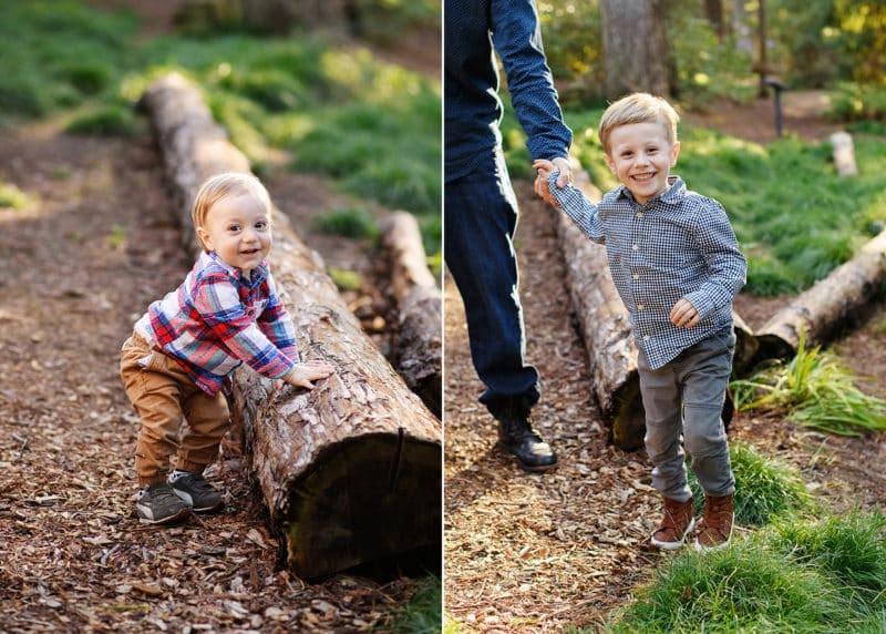 baby boy holding on to a log in the forest and smiling, big brother laughing