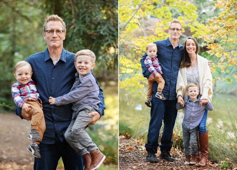 dad holding two young children on his hips, family of four posing in front of fall foliage