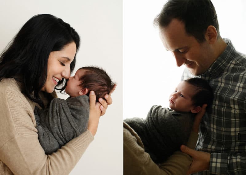 mom touching newborn daughter nose to nose, dad holding baby in studio photo session