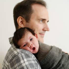 newborn baby boy on dad’s shoulder yawning during family studio session