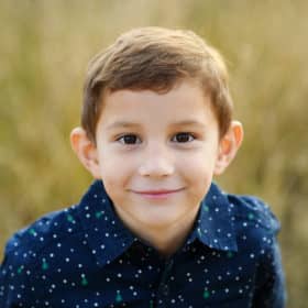 young boy looking up at the camera and smiling during fall family photos in sacramento california