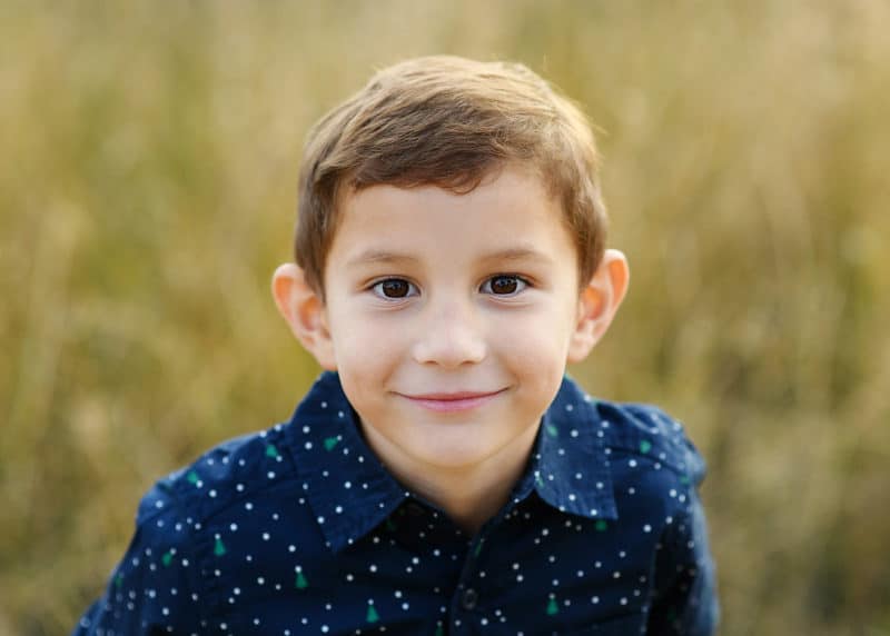 young boy looking up at the camera and smiling during fall family photos in sacramento california