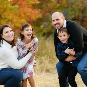 family of four laughing and smiling at the camera during fall family photos in sacramento california