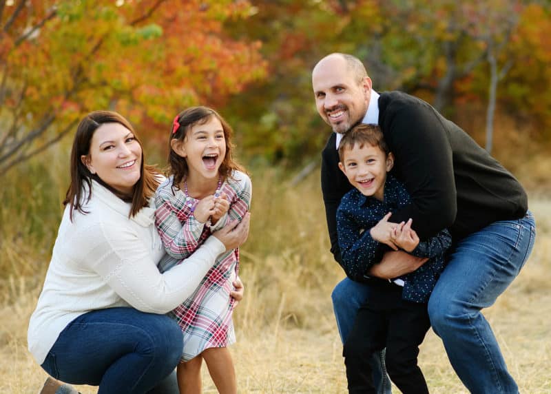family of four laughing and smiling at the camera during fall family photos in lincoln california