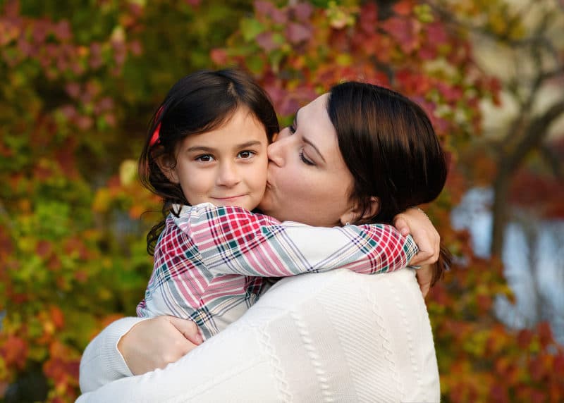 mom kissing young girl on the cheek during fall family photos in sacramento california