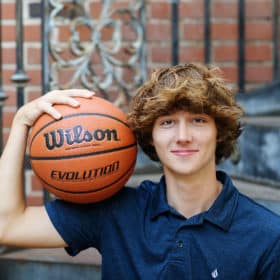 high school senior boy holding a basketball in his arm during senior portraits in sacramento california
