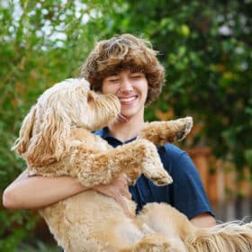 dog giving high school senior boy kiss on the cheek while he smiles