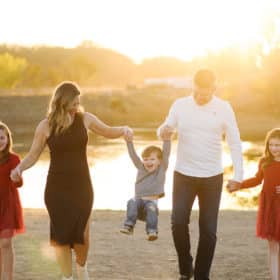 family of five walking together by the river during sunset