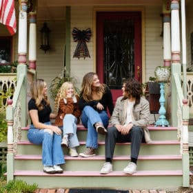 four teenage siblings talking together on the stairs of their family farm in lincoln california