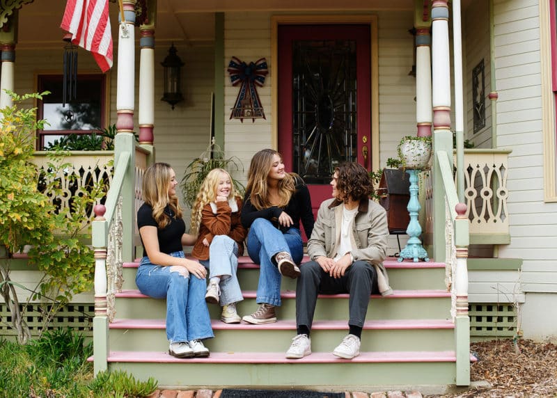 four teenage siblings talking together on the stairs of their family farm in lincoln california