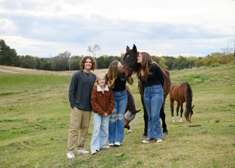 four teenage siblings posing with their horse on the family farm in sacramento california