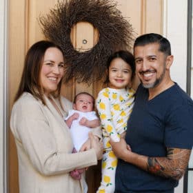 family of four standing outside their front door with newborn baby during at-home photo session in sacramento california