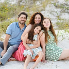 family of four sitting together on the beach in florida during vacation photos