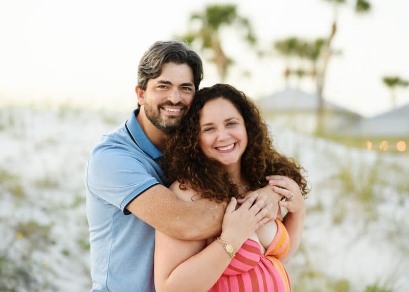 mom and dad standing on the beach during florida vacation smiling at the camera