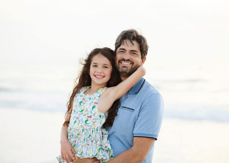 dad and daughter hugging on the beach during family photos in florida