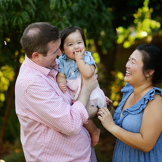 family of three smiling together during a backyard photo shoot in sacramento