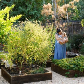 mom with young daughter standing in a green garden in sacramento california