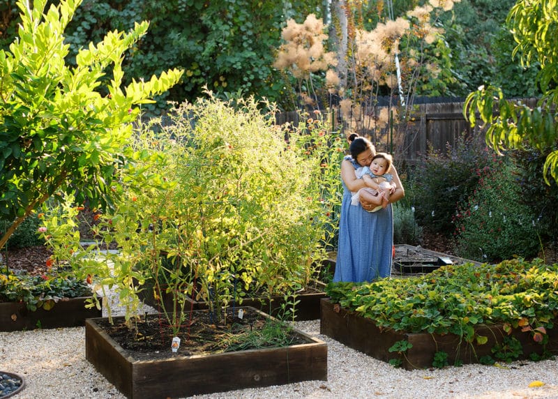 mom with young daughter standing in a green garden in sacramento california