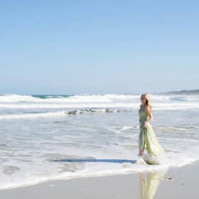senior in college walking along the beach in a green dress in carmel california