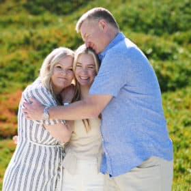 hugging mom and dad while taking senior portraits on the beach in carmel california